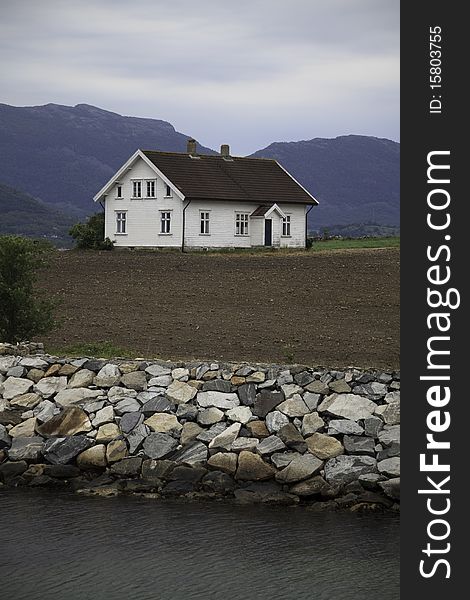 Typical nordic house, placed at the water, steep hills behind, Norway.