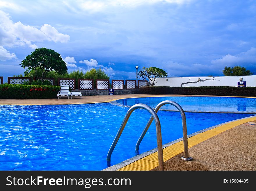 Swimming pool with metallic ladder and blue sky in background. Swimming pool with metallic ladder and blue sky in background