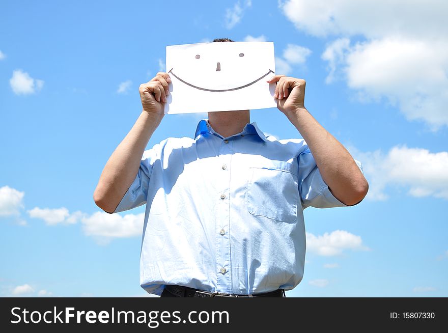 The young man covered his face with a sheet of paper with a picture. The young man covered his face with a sheet of paper with a picture