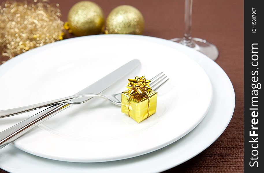 Place setting with golden gift and cutlery. Place setting with golden gift and cutlery