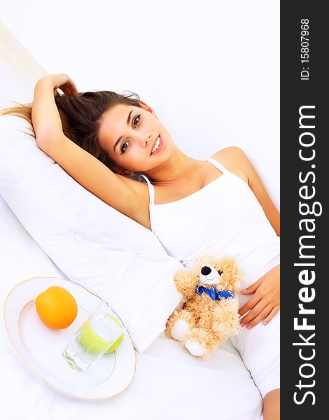 Beautiful girl lying on the bed with a teddy bear. Beautiful girl lying on the bed with a teddy bear