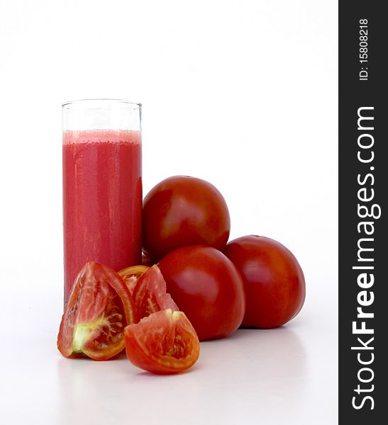 Fresh tomatoes and a glass full of tomato juice isolated on a white background. Fresh tomatoes and a glass full of tomato juice isolated on a white background
