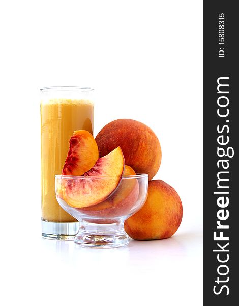 A glass of peach juice in front of peaches isolated on white background. A glass of peach juice in front of peaches isolated on white background.