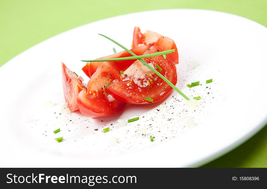 Sliced tomato on plate with chives. Sliced tomato on plate with chives
