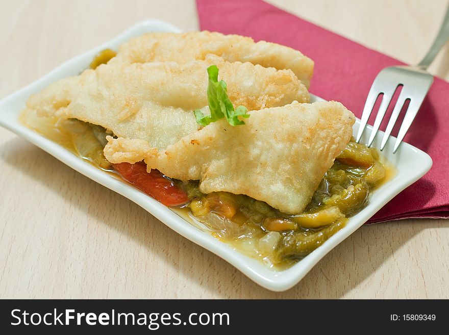 Fried fish fillet with vegetables on white dish