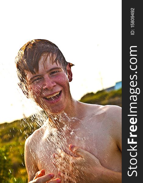 Boy has a shower at the beach after swimming in the ocean