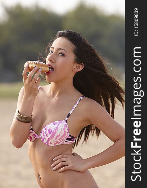 girl with long brown Hair and Bikini,eat to Beach one Doughnut. girl with long brown Hair and Bikini,eat to Beach one Doughnut