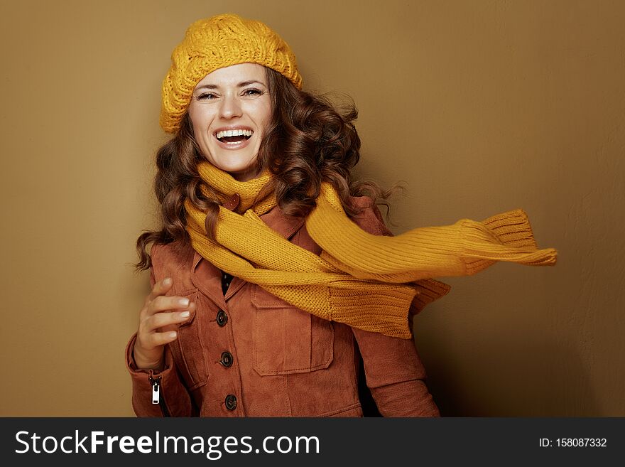 Hello autumn. Portrait of smiling trendy woman in yellow beret and scarf on bronze background. Hello autumn. Portrait of smiling trendy woman in yellow beret and scarf on bronze background