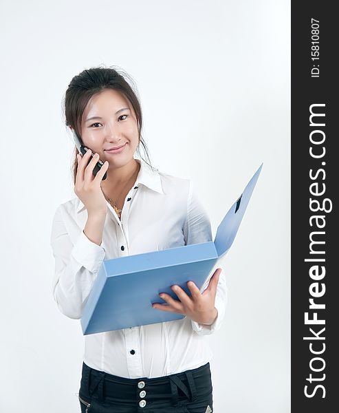 A Beautiful Asian business woman is on the cell phone,who  was carrying a folder