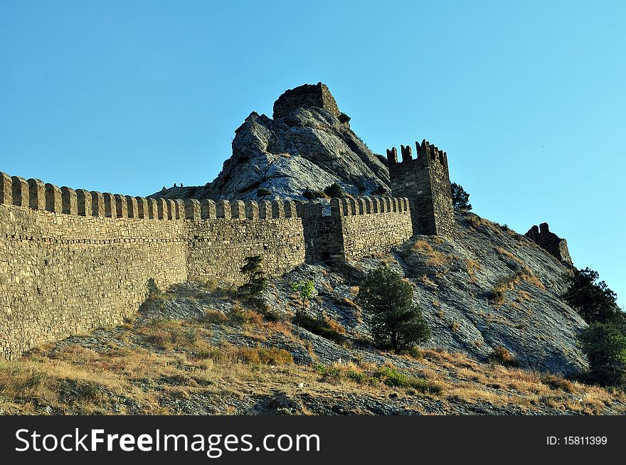 Age-old fortress wall of the Genoese fortress of city pike Perch in Ukraine on a background dark blue sky