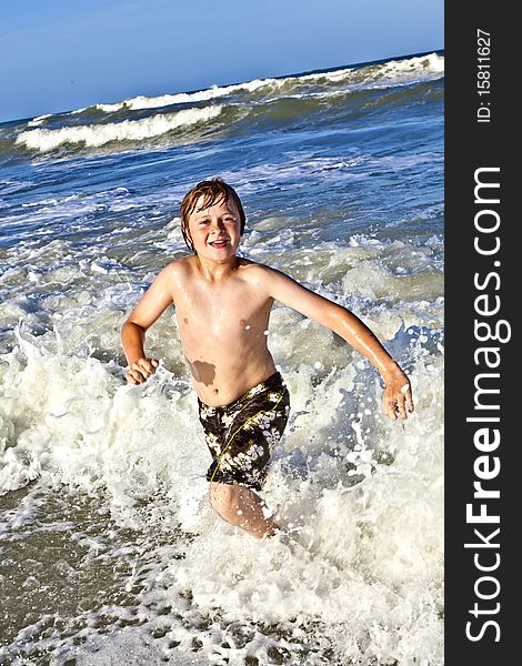Young happy boy enjoys the waves of the blue sea