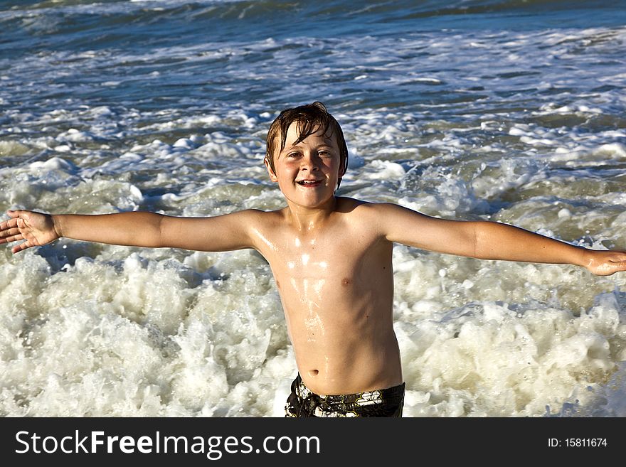 Young happy boy enjoys the waves of the blue sea