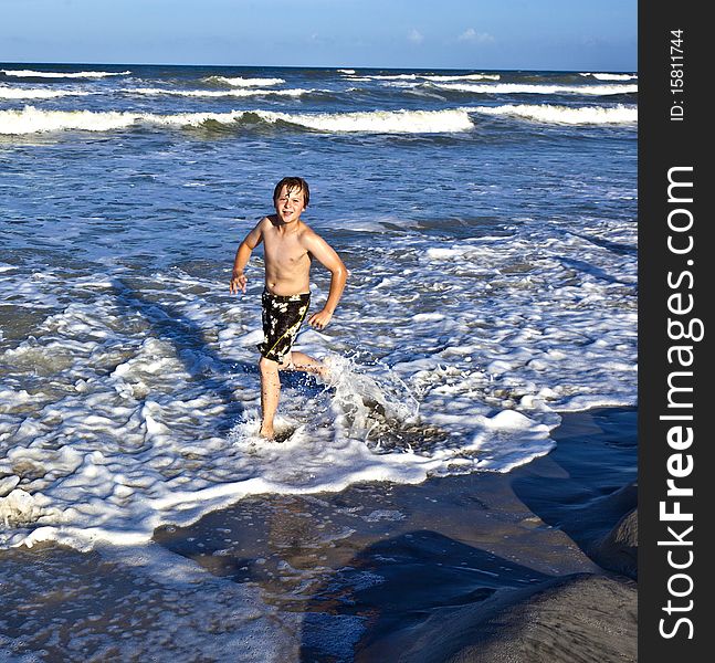 Young happy boy enjoys the waves of the blue sea