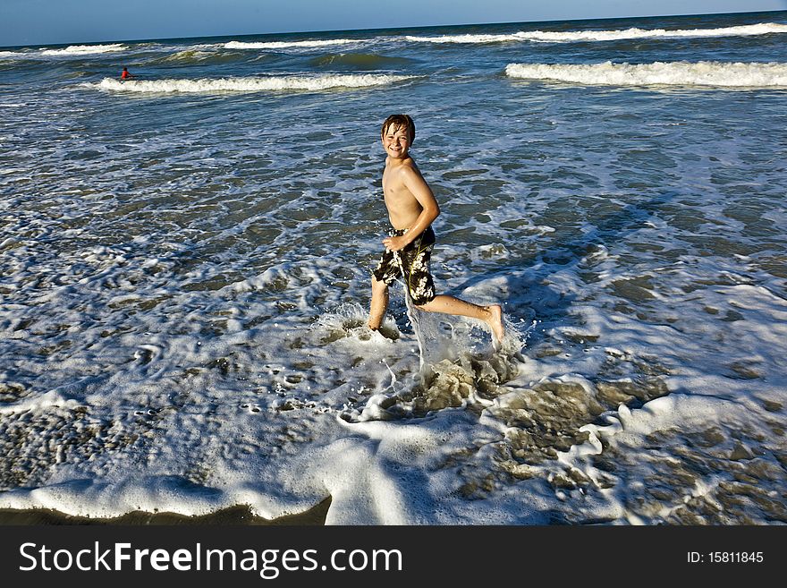 Young Boy Enjoys The Waves Of The Blue Sea