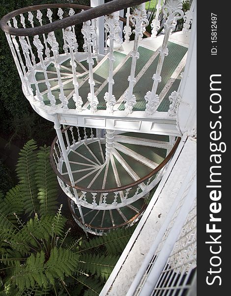 A view from above of a white metal spiral staircase in victorian style. A view from above of a white metal spiral staircase in victorian style