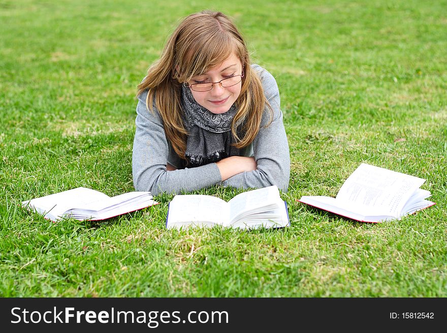 The girl lays on a green grass, and reads the book. The girl lays on a green grass, and reads the book