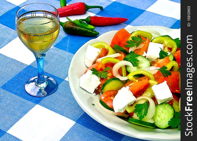 Salad of tomatoes, cucumbers, cheese and a cup of brandy on the cover of blue and white squares. Salad of tomatoes, cucumbers, cheese and a cup of brandy on the cover of blue and white squares