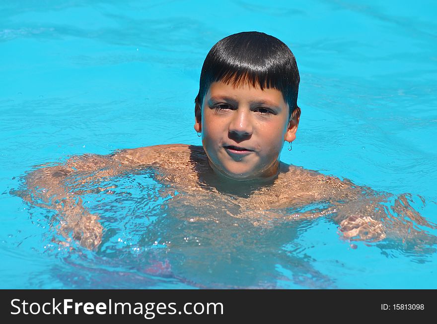 A Hispanic boy is swimming in a summer camp. A Hispanic boy is swimming in a summer camp