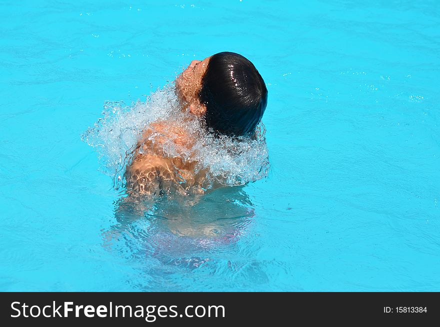 A swimmer is emerging from the water in a swimming pool. A swimmer is emerging from the water in a swimming pool