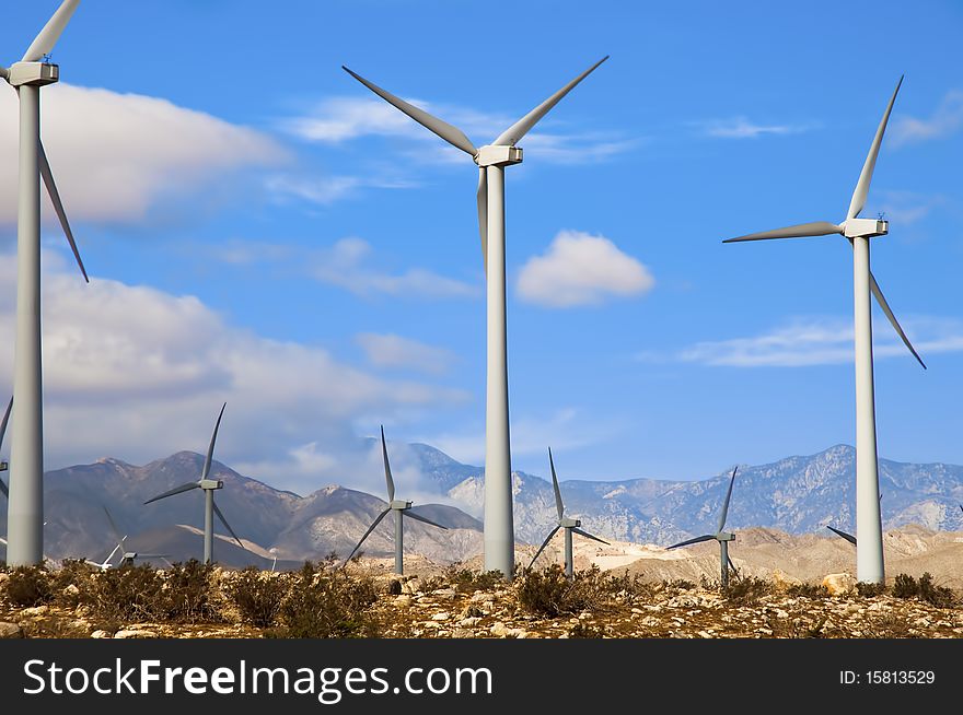 Wind turbines in a desert setting with mountains in the background