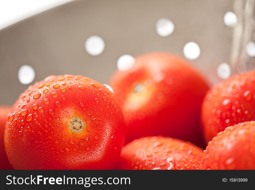 Macro of Fresh, Vibrant Roma Tomatoes in Colander with Water Drops Abstract.