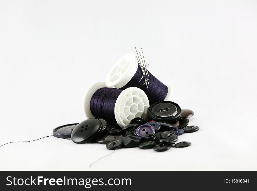 Time to sew, spools of thread with needles piled upon matching color buttons. Time to sew, spools of thread with needles piled upon matching color buttons