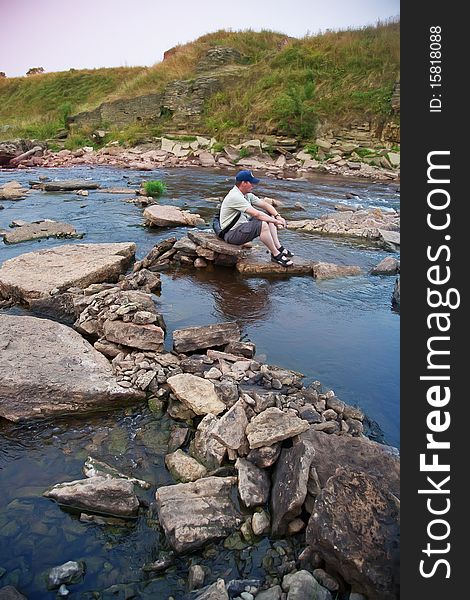 Man sitting on river stone. Man sitting on river stone