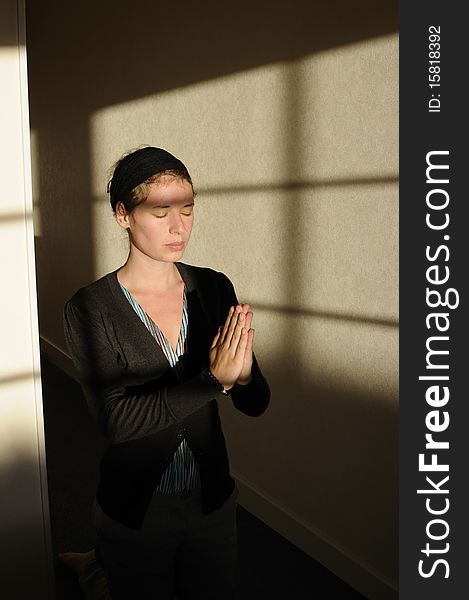 Young woman with closed eyes praying in little church. Young woman with closed eyes praying in little church