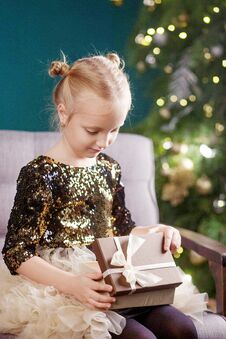 Christmas And New Year Celebration Concept. Pretty Little Girl Playing And Being Happy About Christmas Tree And Lights. Stock Photos