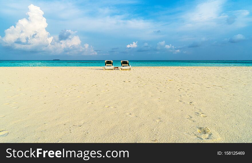 Along the azure sea there are sun loungers for visitors to relax. Maldives, the concept of family vacations, tourism. Along the azure sea there are sun loungers for visitors to relax. Maldives, the concept of family vacations, tourism.