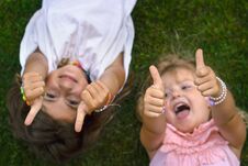 Two Little Girls Laying On The Grass, Laughing And Showing Thumbs Up Stock Photos