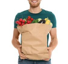 Young Man With Bag Of Fresh Vegetables On White Background Stock Images