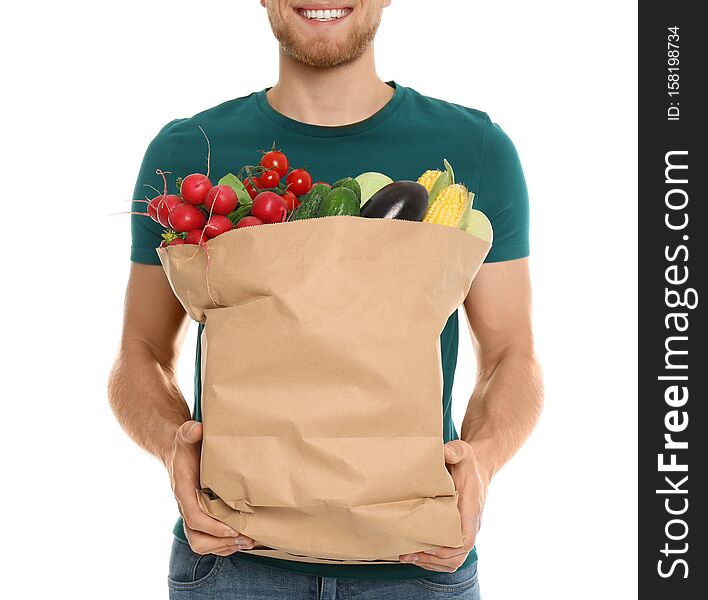 Young man with bag of fresh vegetables on white background, closeup