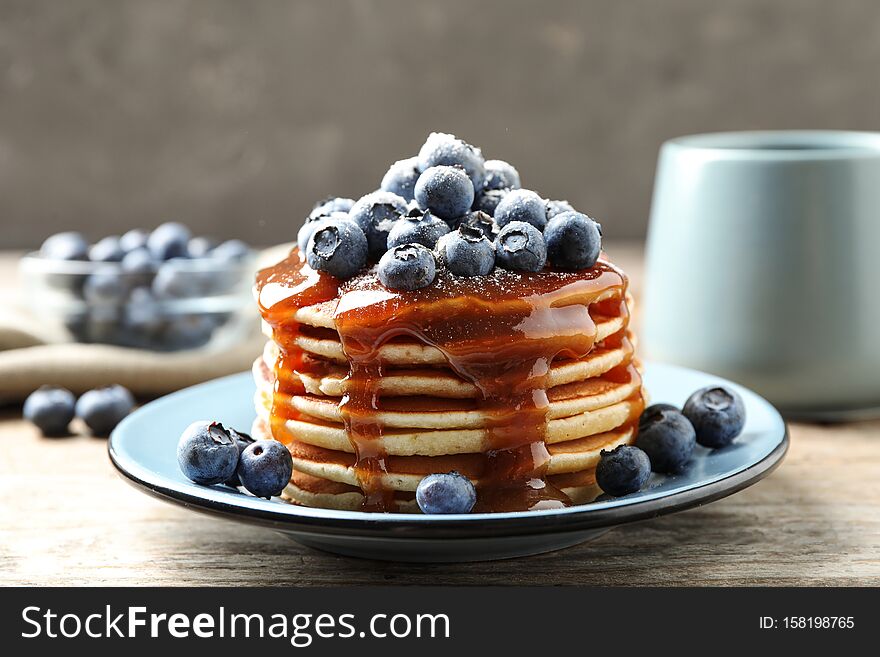 Delicious pancakes with fresh blueberries on wooden table