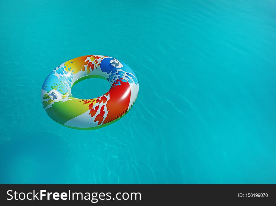 Colorful inflatable ring floating in swimming pool on sunny day