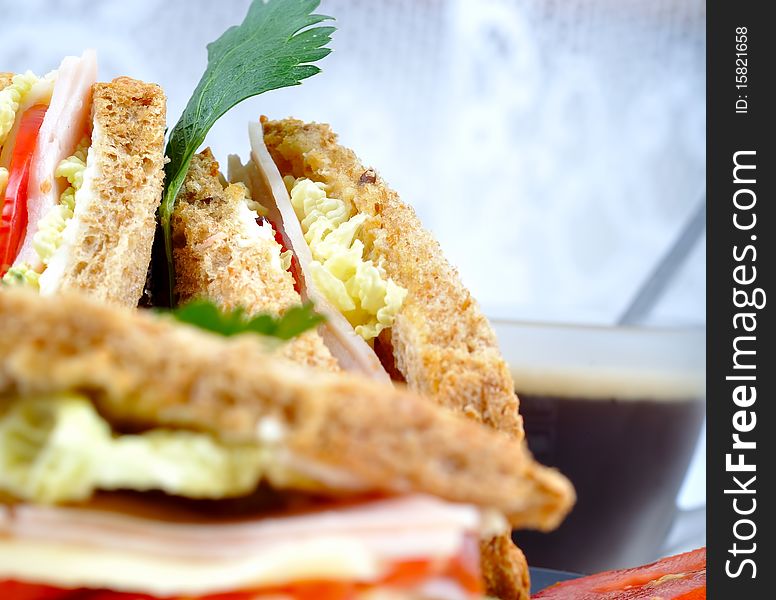 Close up fresh and delicious classic club sandwich over a black glass dish with coffee and vegetable