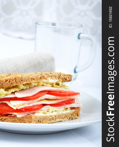 Fresh and delicious classic club sandwich over a white glass dish with glass cup. Fresh and delicious classic club sandwich over a white glass dish with glass cup