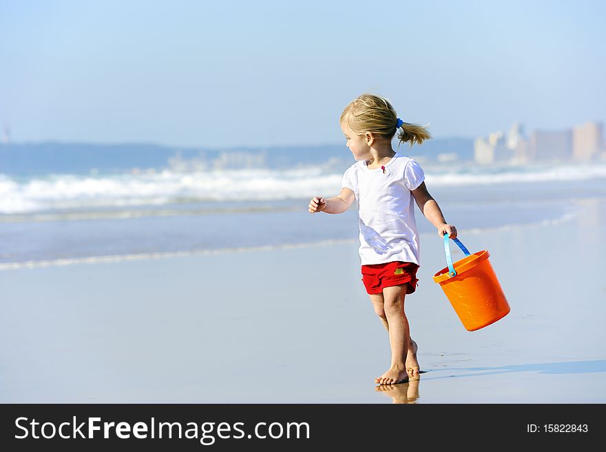 Cute little girl walks along the ocean edge looking for shells. Cute little girl walks along the ocean edge looking for shells