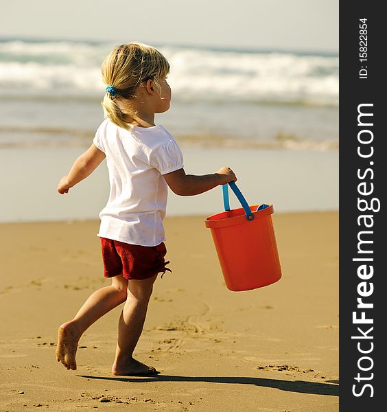Adorable little blonde girl with her bucket at the beach. Adorable little blonde girl with her bucket at the beach