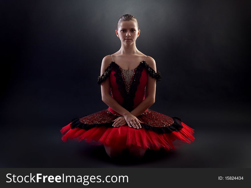 Picture of a seated ballerina wearing a red tutu