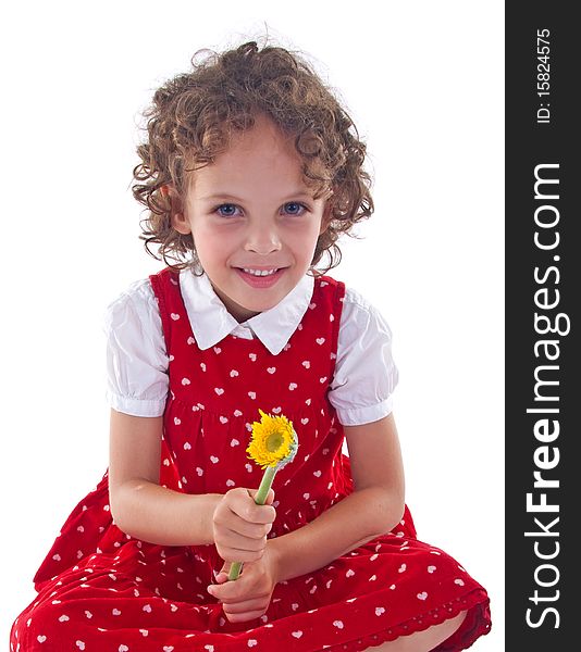 Little girl wearing red dress is stitting with a flower in her hand