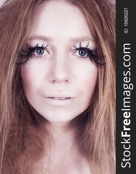 A glamorous, high fashion woman with exaggerated eyelashes stares into camera. Vertical shot. A glamorous, high fashion woman with exaggerated eyelashes stares into camera. Vertical shot.