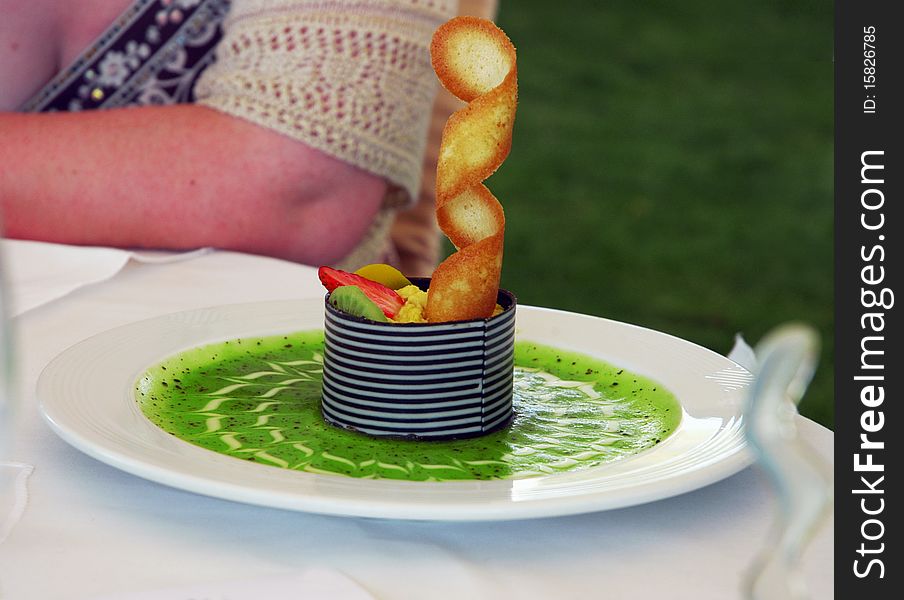Fruit dessert with green kiwi sauce on white plate