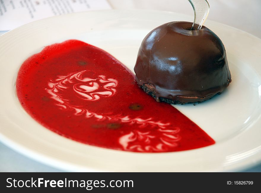 Chocolate dessert with red strawberry sauce on white plate. Chocolate dessert with red strawberry sauce on white plate