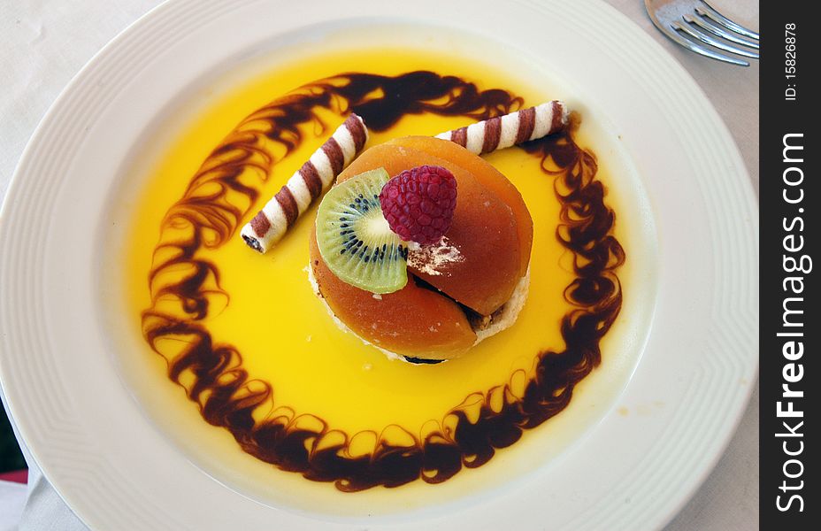 Sweet fruit dessert with yellow sauce on white plate