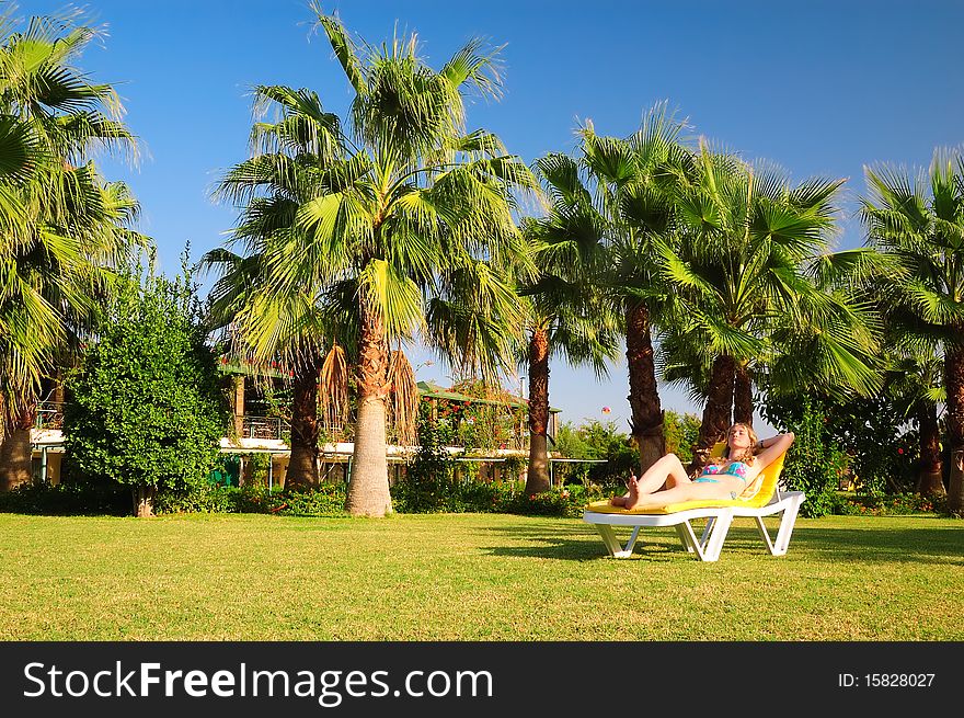 The teenager sunbathes near a palm tree. The teenager sunbathes near a palm tree