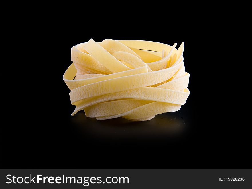 Raw dry nest pasta with reflection isolated on black