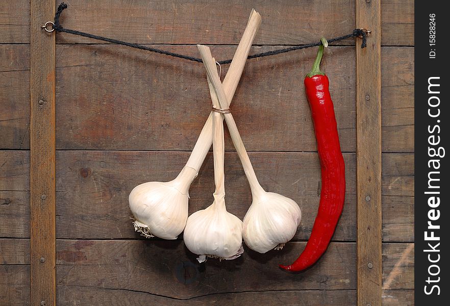 Garlic and chili pepper hanging with rope on wooden background. Garlic and chili pepper hanging with rope on wooden background