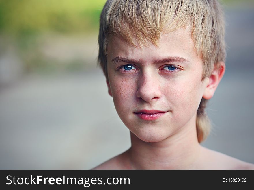 The serious boy with blue eyes on the nature