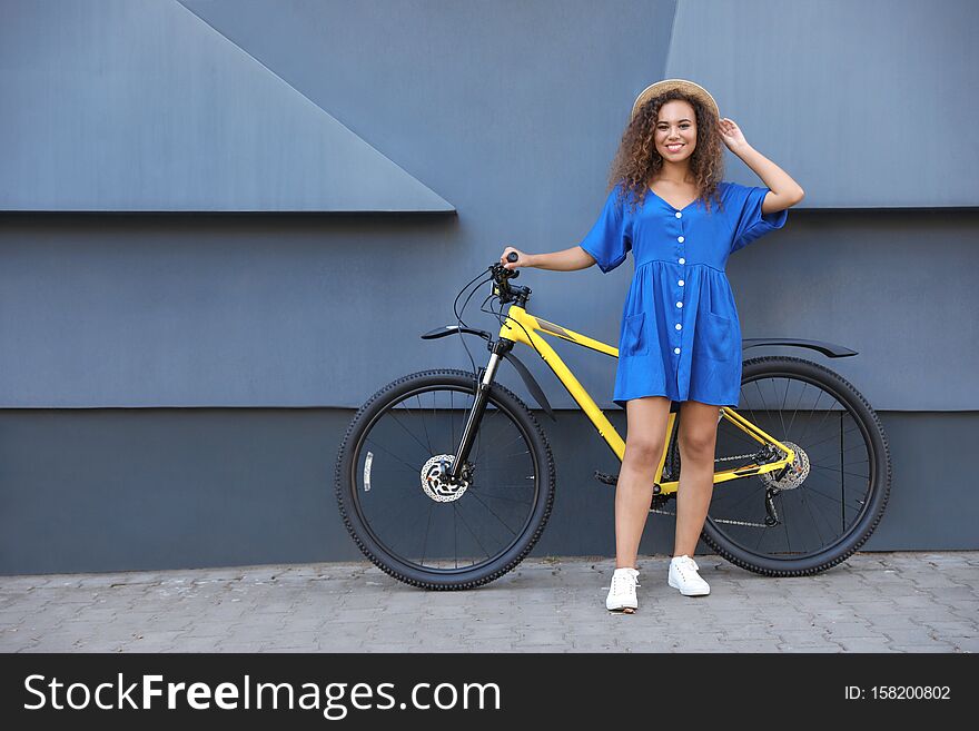 Beautiful Young African-American  With Bicycle Near Grey Wall On City Street. Space For Text